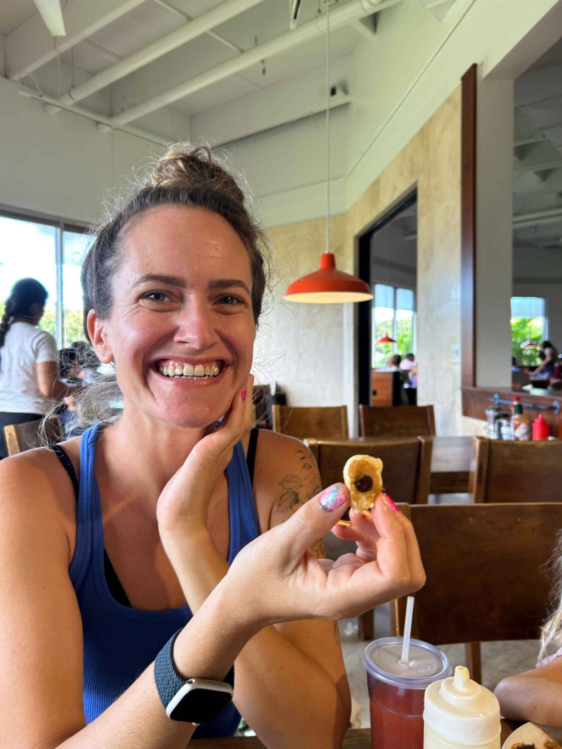 Mom smiles at small pancake her daughter made while at Slappy Cakes on Maui