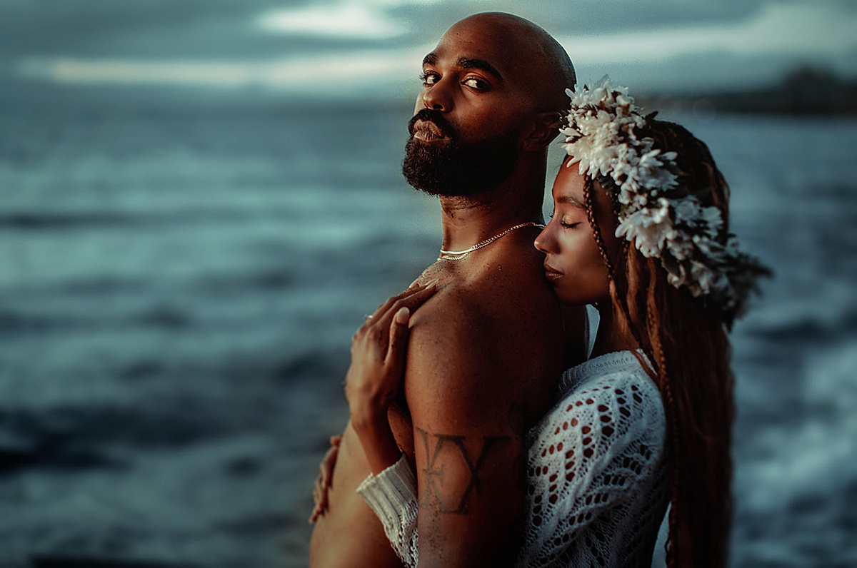 A couple embraces on a Maui beach during blue hour, the sky fading into deep shades of blue