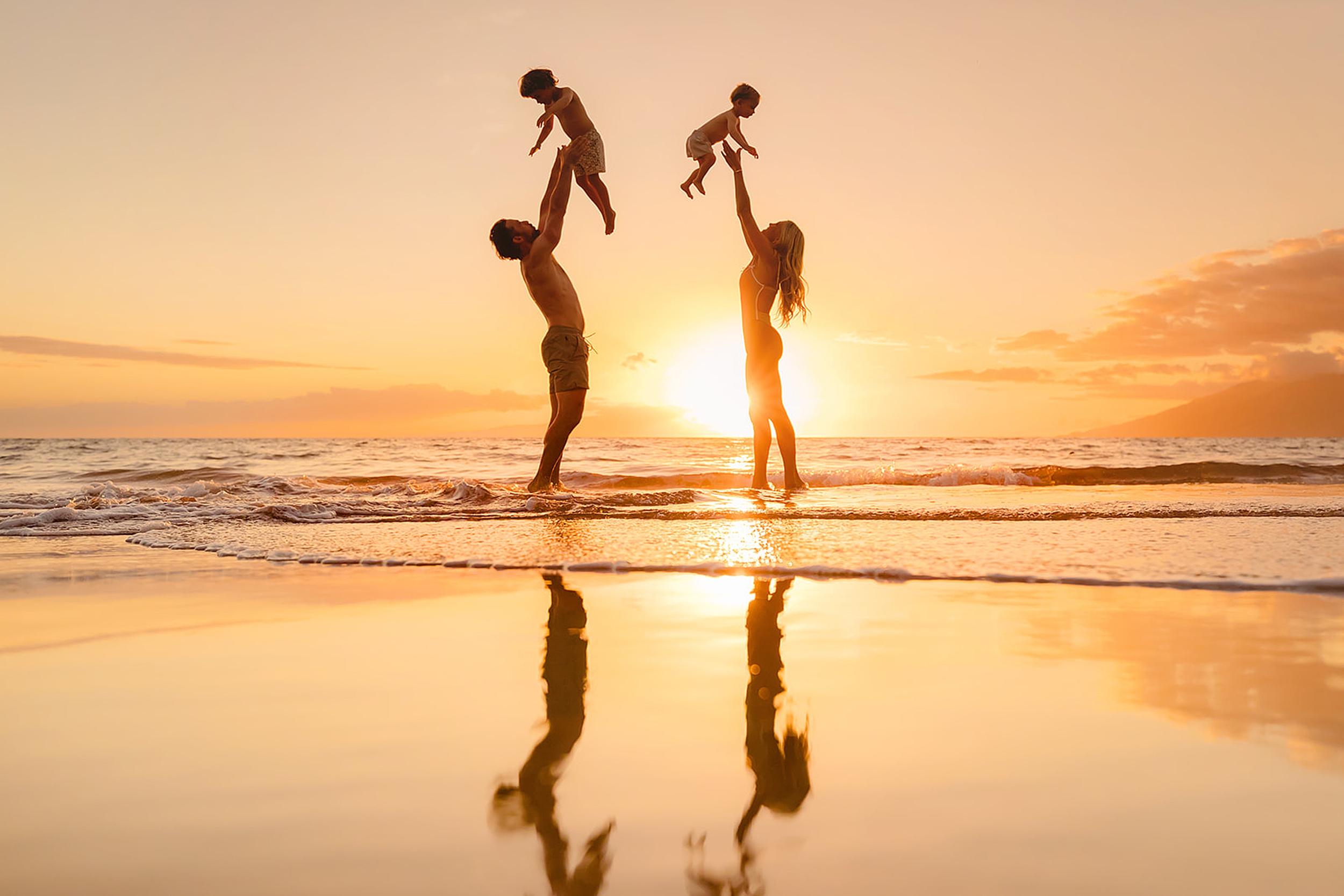 Parents enjoying a candid moment with their children in Wailea’s scenic beach setting, ideal for families staying in Kihei condos.