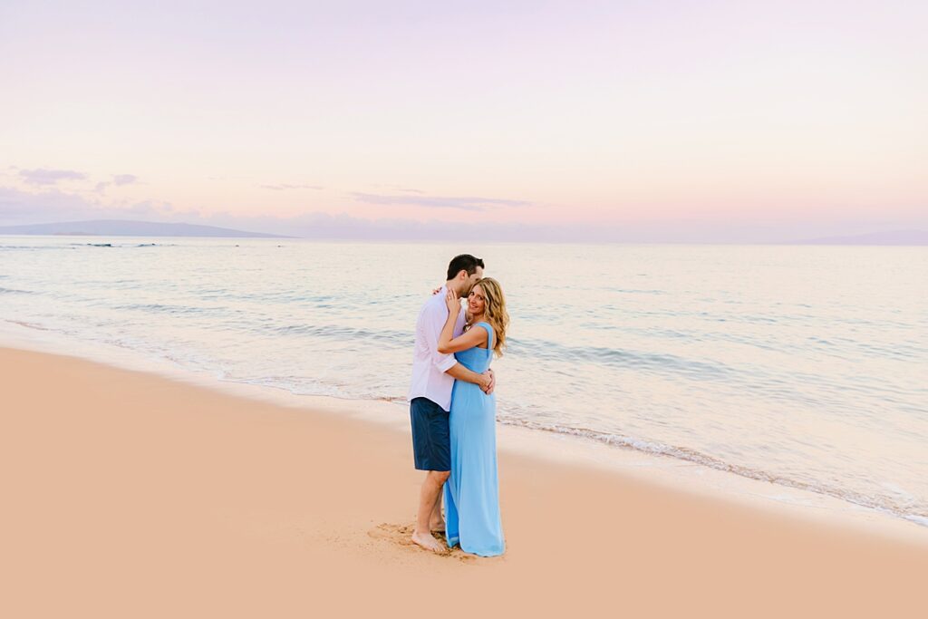 Couple who are on their honeymoon kiss on the beach at sunrise on Maui