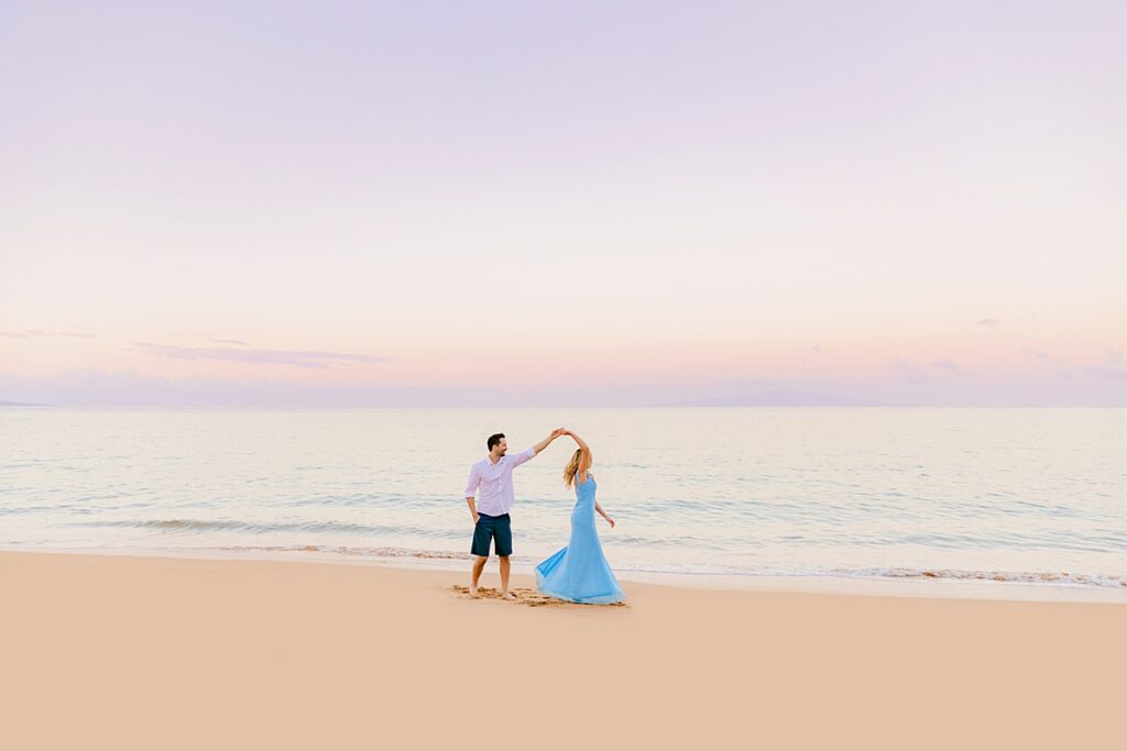 Man twirls his new bride on the beach just before sunrise, photographed in Wailea by love and water