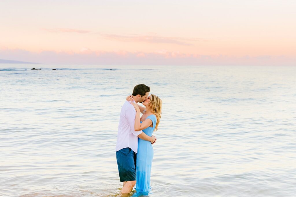 honeymoon portraits on maui featuring a couple kissing in the ocean at sunrise