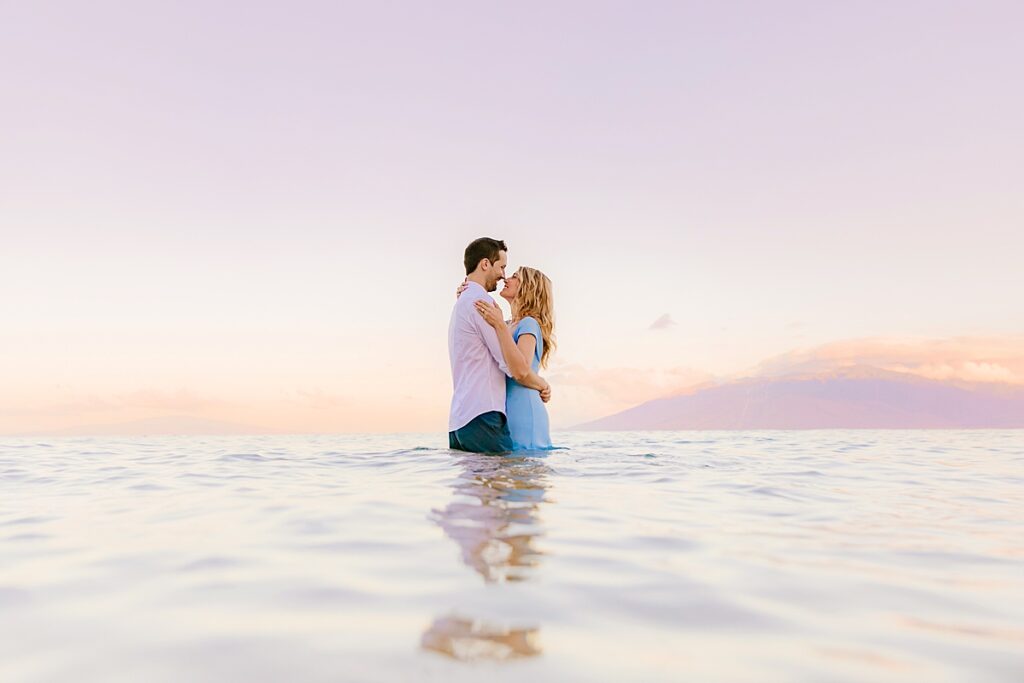 couple embrace in the ocean as love and water photography shoot their maui honeymoon portraits 