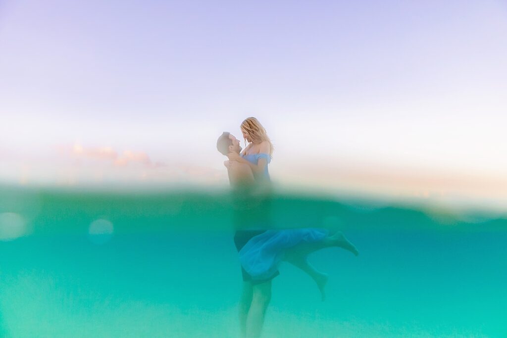 maui honeymoon portraits captured in the ocean by love and water, half underwater with a pastel pink sky