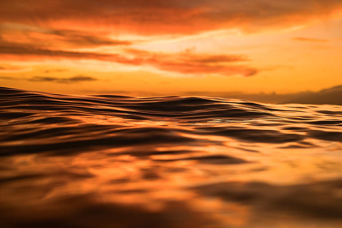 The ocean in Wailea, Maui after a storm is glowing red and orange at sunset