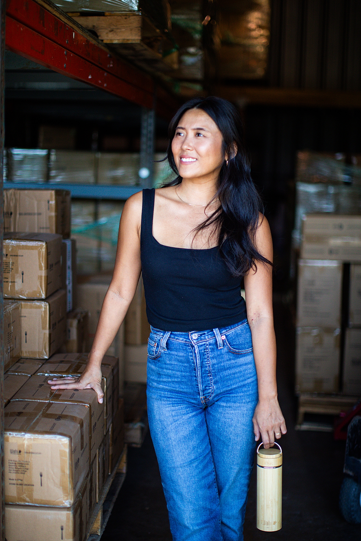 woman rests hand on boxes while looking out of her warehouse in Kahului that services local businesses