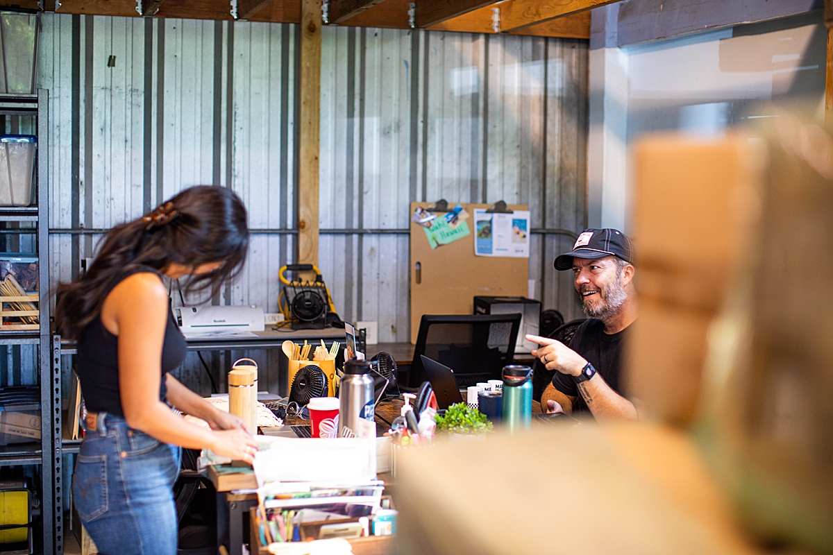 woman chats with husband filling orders at sustainable business on maui