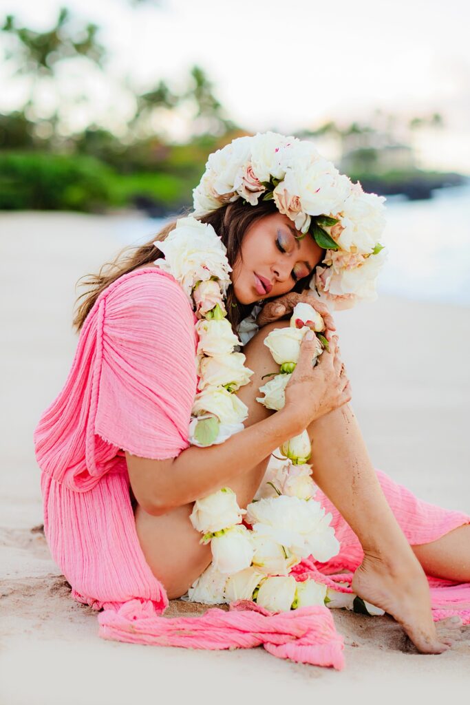 Woman in a Kasia Kulenty gown with eyes closed during her Wailea sunrise portraits, her floral lei po’o framed by the soft, glowing hues of the Maui sunrise.