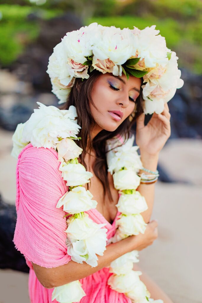 A dreamy sunrise close-up of a woman in Wailea wearing a floral lei of pastel blooms encircling her hair photographed by love and water