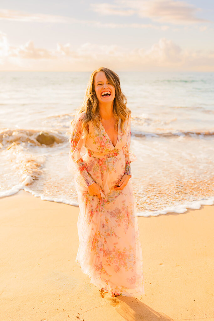 Pregnant woman laughs while wearing a soft tulle maxi dress from Baltic Born, captured by Love and Water Photography.