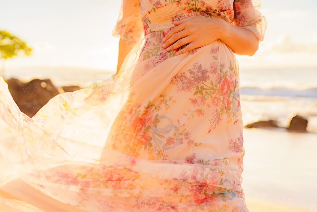 Romantic maternity portrait of a pregnant woman at 24 weeks in a Baltic Born tulle maxi dress, with details flowing in the wind