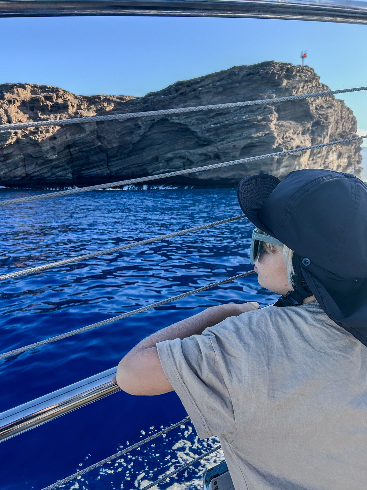 boy with black sun hat and sunglasses looks at the ocean before snorkeling aboard a wailea boat tour