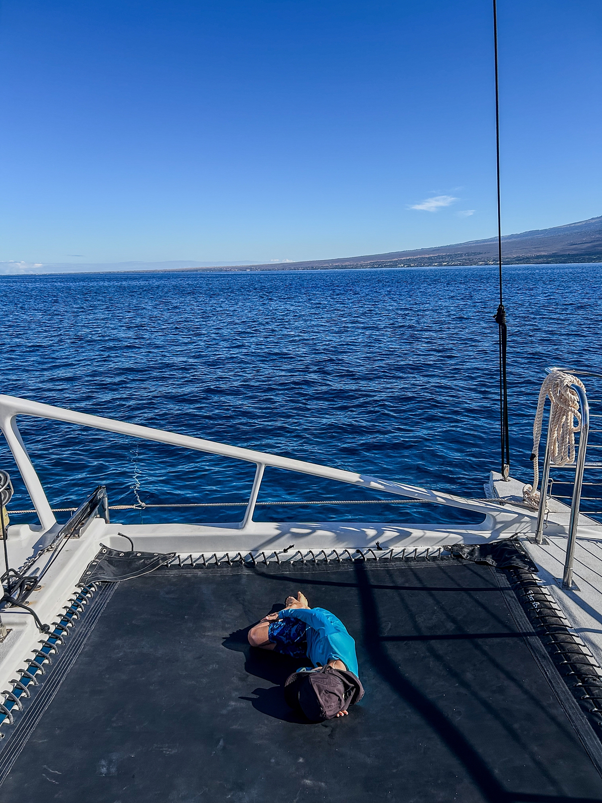 boy relaxes on the trampoline on a sail maui boat during his snorkel to molokini