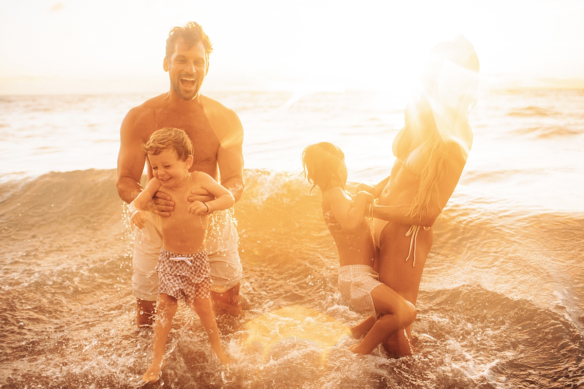 family in the ocean with water splashing at sunset in wailea, maui