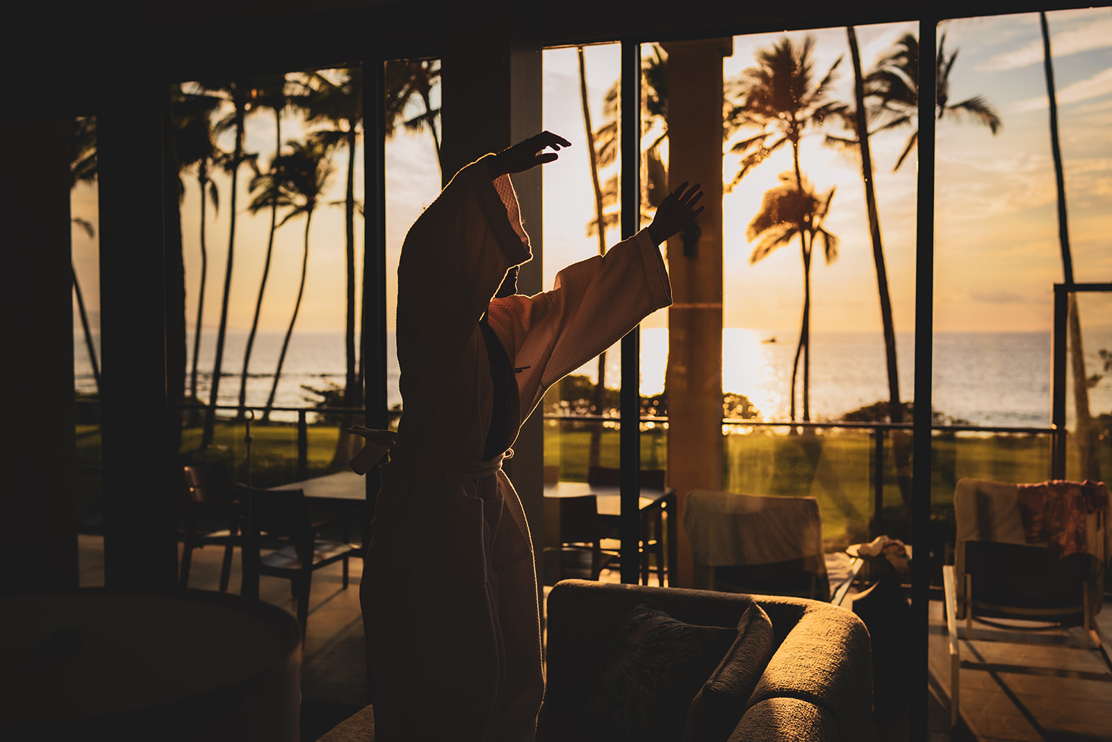 Boy jumps on the couch silhouetted by the setting sun at Andaz Maui at Wailea resort photographed by love and water photography