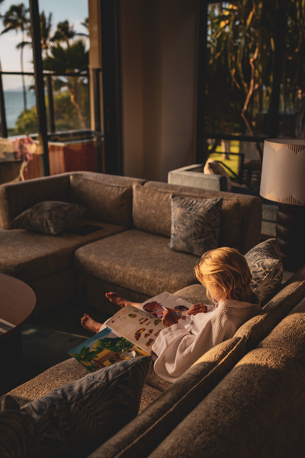 girl plays with a sticker book on the couch having some downtime during their maui family vacation