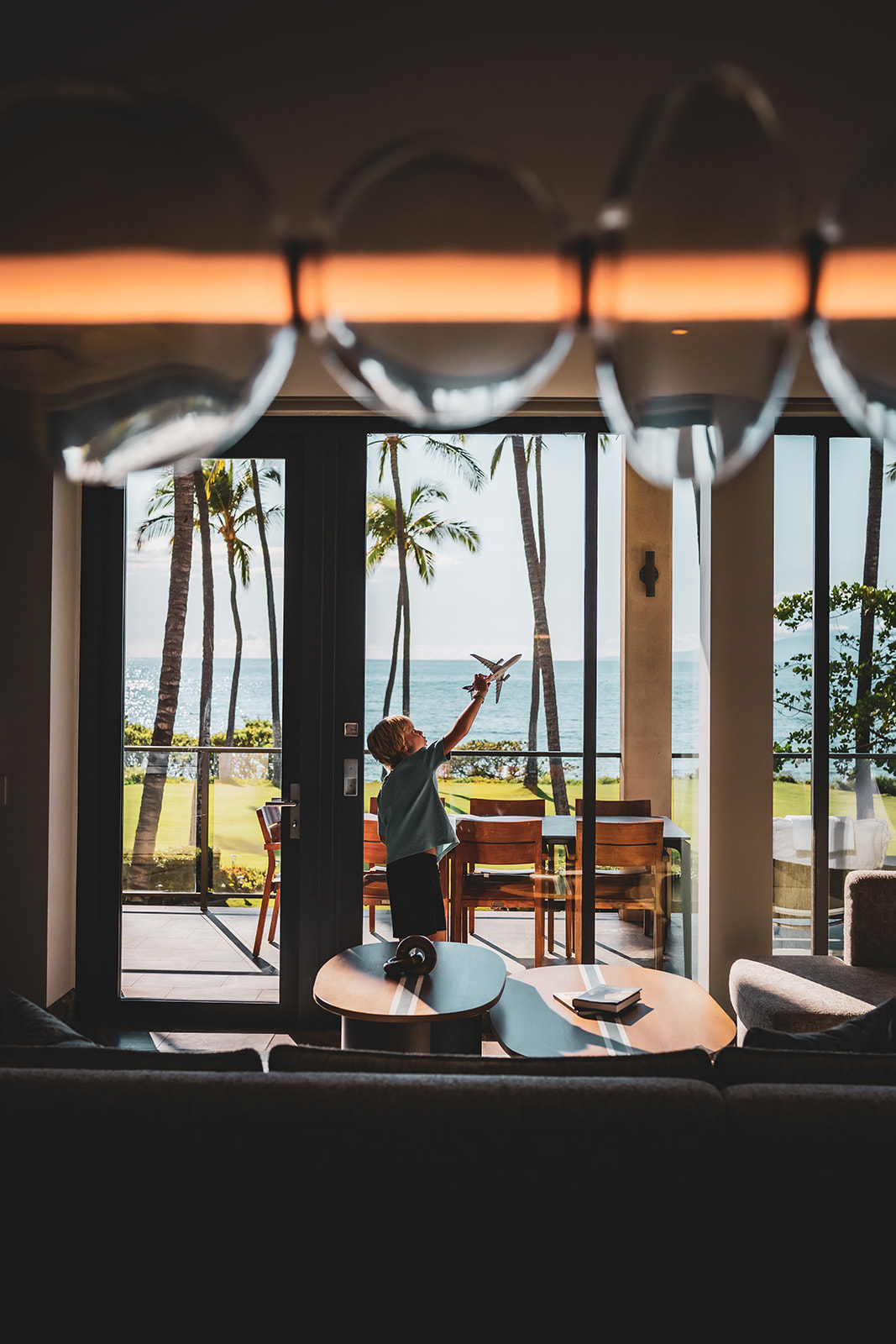 Young boy holding a Hawaiian Airlines toy in front of an expansive view at the Makai Oceanfront Villa at Andaz Maui at Wailea Resort