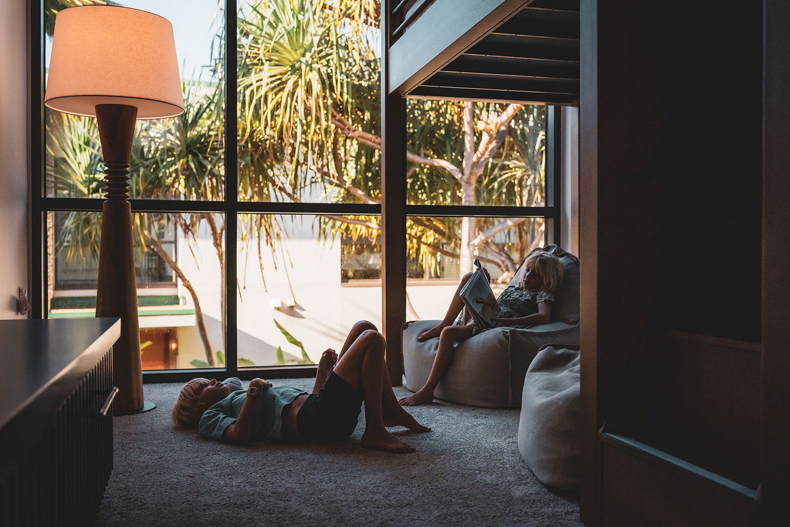 young boy and girl relax at andaz maui resort framed by pandanus trees