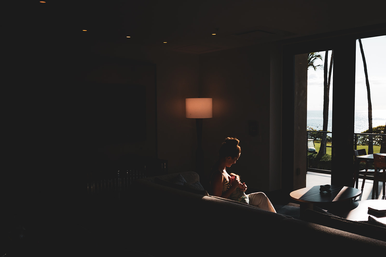 woman bonds with her baby breastfeeding on a couch in a dimly lit room